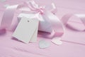 White gift box with a pink satin bow and ribbon on pink wooden background. Mock up with paper kraft tag is included for Royalty Free Stock Photo