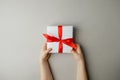 White gift box with red bow in the children`s hands on gray background, Shopping, sale, mother day, valentine, christmas