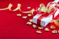White gift box with red and gold ribbon, and a small gold hearts shape on a red velvet floor, Valentine\'s day Royalty Free Stock Photo