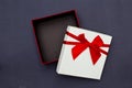 White gift box with red ribbon on black background.