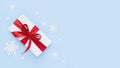 White gift box with red ribbon on blue frosty background