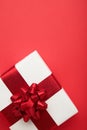 White gift box with red ribbon bow on red background. Christmas concept. Vertical photo Royalty Free Stock Photo