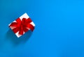 White gift box red ribbon bow blue background Royalty Free Stock Photo