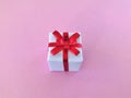 White gift box red ribbon bow on pink background Royalty Free Stock Photo