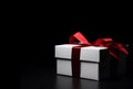 White gift box with red satin ribbon bow isolated on black Royalty Free Stock Photo