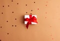 White gift box with a red satin ribbon bow tied on brown background with red stars shapes.Christmas Holidays and present concept Royalty Free Stock Photo