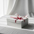 White gift box on a table, adorned with a vibrant red ribbon Royalty Free Stock Photo