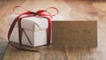 White gift box with thin red ribbon bow on old wood table with i love you paper card Royalty Free Stock Photo