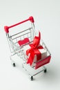 White gift box tied with red ribbon in a shopping cart Royalty Free Stock Photo