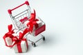 White gift box tied with red ribbon in a shopping cart Royalty Free Stock Photo