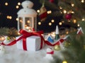 White gift box on wool cloth with christmas decoration against blurry lantern and decorated christmas tree with bokeh lights Royalty Free Stock Photo