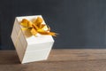 White gift box and yellow ribbon with tag on wood table with spa Royalty Free Stock Photo