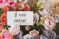 white gift card with the inscription I love you in Russian in a bouquet of bright beautiful multi-colored roses Royalty Free Stock Photo