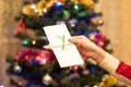 White gift envelope in a female hand with Christmas tree with or