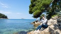 White girl smiling taking a photo by the sea with smart phone taking selfie at rock. Summer vacation at tropical paradise beach. Royalty Free Stock Photo