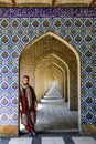 White girl tourist with a head covered stands near the beautiful gate decorated in Persian style