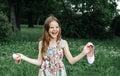 Girl 10 years old in a dress holding shoes in her hands and laughing in a clearing in nature rejoicing in nature