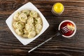 White bowl with dumplings and dill, pepper shaker, dumpling on fork on bowl with ketchup on wooden table. Top view Royalty Free Stock Photo