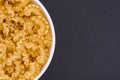 White glass bowl of raw pasta. Isolated on a dark grey background. Royalty Free Stock Photo