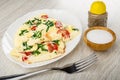 White dish with omelette with tomato and parsley, salt in bowl, pepper shaker, fork on wooden table Royalty Free Stock Photo