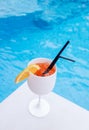 White glass of orange color cocktail with straws against poolside at resort hotel during vacation Royalty Free Stock Photo