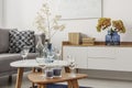 White glasses and candles on two small coffee tables in bright living room interior