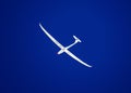 White glider aircraft or sailplane in the clear blue sky over the KlÃÂ¶ntal swiss alpine valley Kloental or Klontal Royalty Free Stock Photo