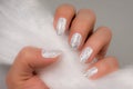 White glittered nails on gray background