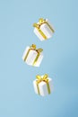 White glossy gift boxes with shiny golden ribbon on blue background, 3d illustration. Royalty Free Stock Photo