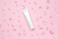 White glossy plastic tube with flower petals for medicine or cosmetics, cream, gel, skin care, toothpaste on pastel pink Royalty Free Stock Photo