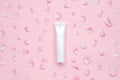White glossy plastic tube with flower petals for medicine or cosmetics, cream, gel, skin care, toothpaste on pastel pink Royalty Free Stock Photo
