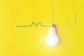 White glowing light bulb Against Yellow Background with wires phase, zero, ground. Idea, innovation, creativity concept, design Royalty Free Stock Photo