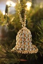 White and gold beaded bell ornament hanging on Christmas tree