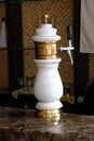 White and gold beer tap with classic design at a marble bar