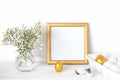 White and gold Easter eggs  a mockup with a gold frame and spring flowers in a vase on a white wooden table Royalty Free Stock Photo
