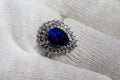 white gold jewelry ring in close-up with a large blue pear-cut sapphire and diamonds on the river in a white glove Royalty Free Stock Photo