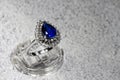 white gold jewelry ring with a large blue pear-cut sapphire and diamonds on a gray background Royalty Free Stock Photo