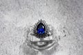 white gold jewelry ring with a large blue pear-cut sapphire and diamonds on a gray background Royalty Free Stock Photo
