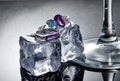 White gold rings with amethyst and blue topaz on ice cubes on a gray background with reflection. Jewelry art and product sales Royalty Free Stock Photo