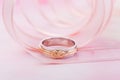 White gold wedding rings with pink gold knot on pink background with ribbon