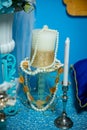 White-Golden candle wrapped with pearl beads on a glass candlestick. White candle in a silver candlestick. On the background of a