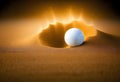 White golf ball in golden dry sand explosion on black background