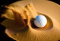 White golf ball in golden dry sand explosion on black background