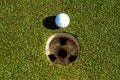 A white golf ball sitting at the cup Royalty Free Stock Photo