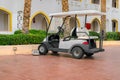 A white Golf cart is parked near the hotel complex. The electric car is charged in the Parking lot of the resort city. A car Royalty Free Stock Photo