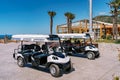 White golf carts stand in a tiled parking lot in front of the hotel among palm trees Royalty Free Stock Photo