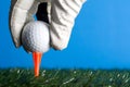 White Golf Glove Hand Putting a Ball on a Orange Tee with Blue Sky Royalty Free Stock Photo