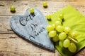 White grapes on wooden table, wooden heart with spanish text