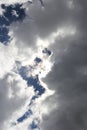 White-gray clouds in the sky, puffed clouds and the sun shining through in the background, blue sky Royalty Free Stock Photo