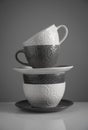 White and gray tea cups and soup cups stacked on a gray background